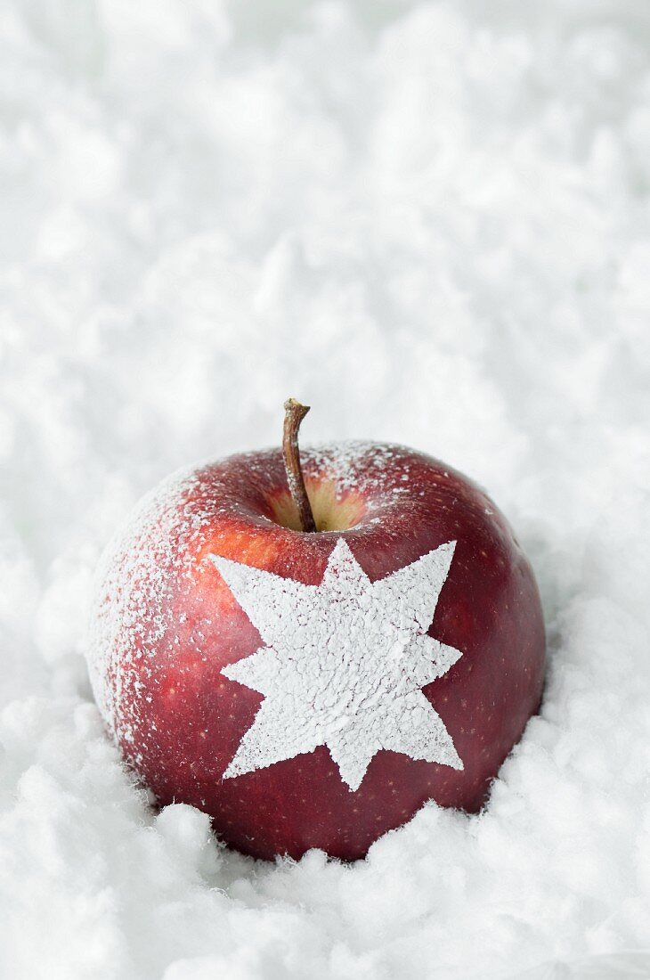 Roter Apfel mit Sternmotiv im Schnee