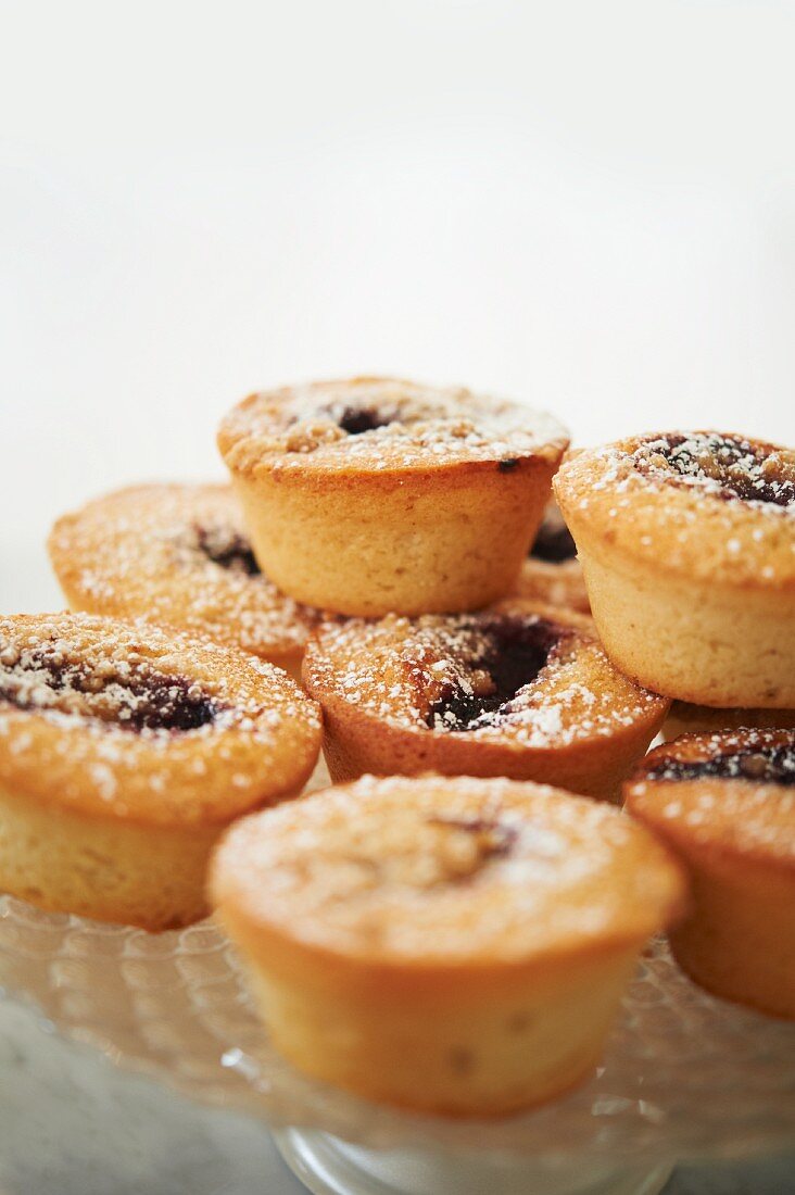 Jam Filled Muffins Dusted with Powdered Sugar on a Glass Cake Stand