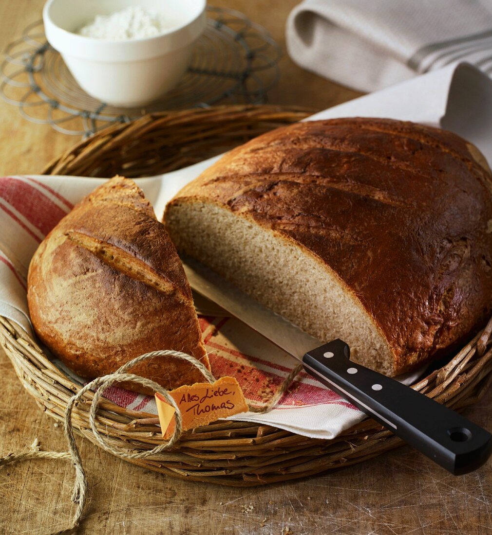 A crusty loaf, sliced open, in a bread basket