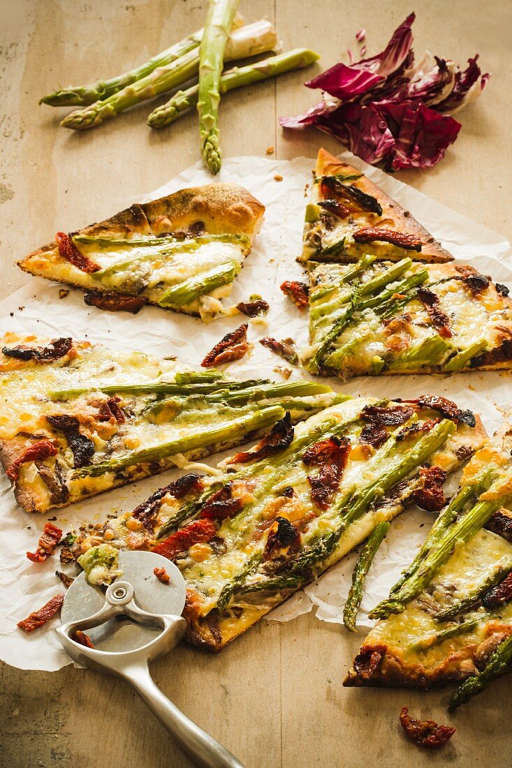 Pizzastücke mit grünem Spargel und getrockneten Tomaten