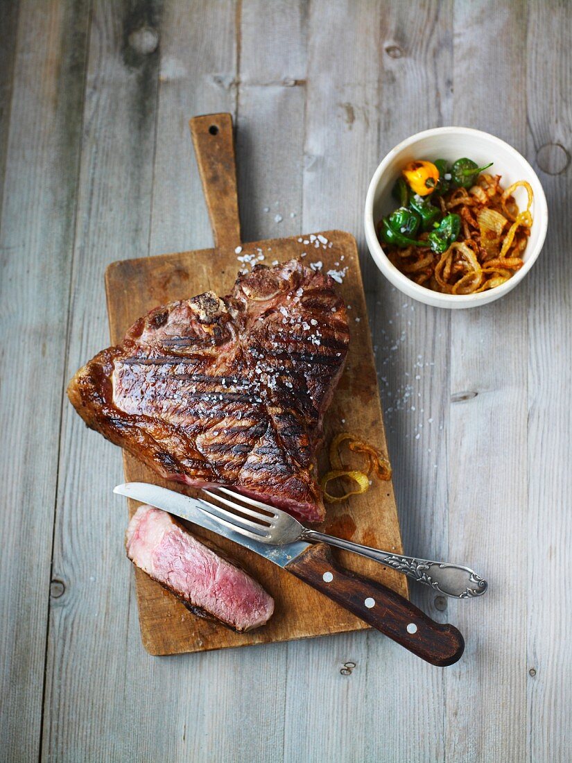 Gegrilltes T-Bone-Steak mit Zwiebeln auf Schneidebrett