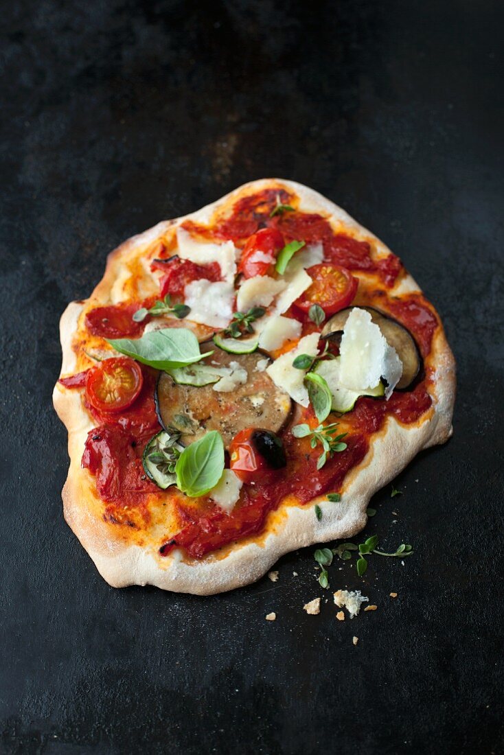 Pizza topped with tomatoes, aubergines, parmesan and basil