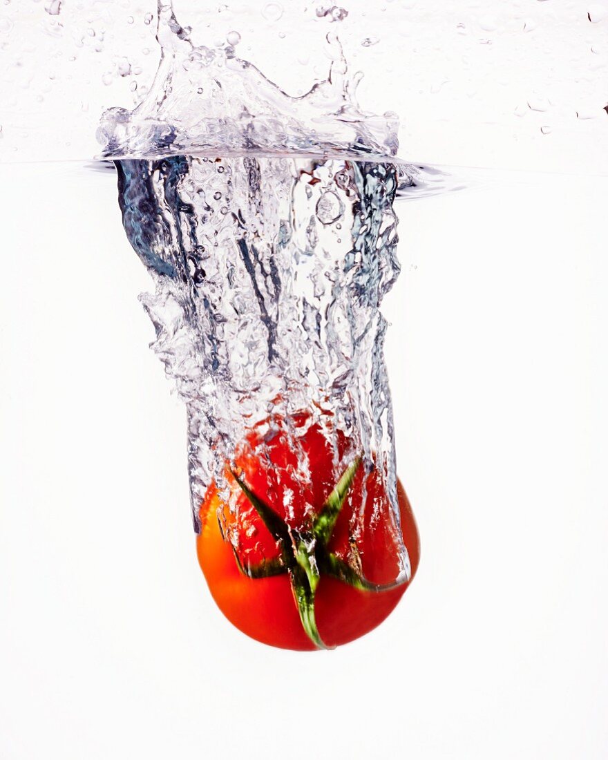 Eine Tomate fällt ins Wasser