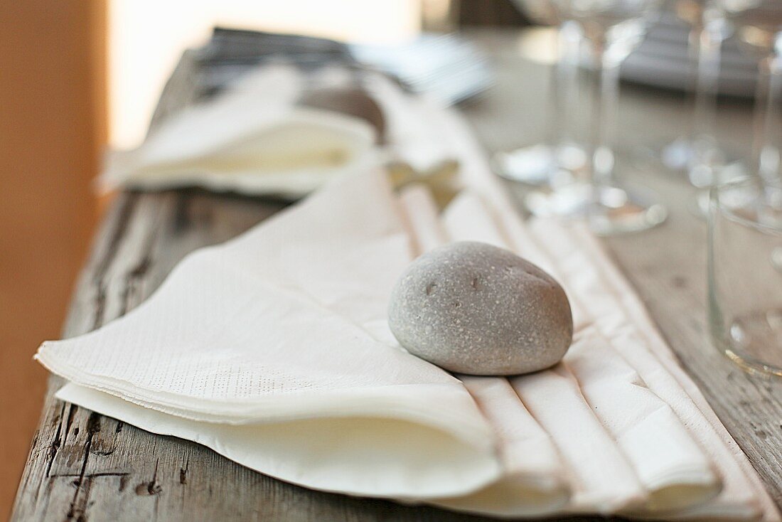 Papierservietten mit einem Stein als Beschwerer auf einem Tisch im Freien