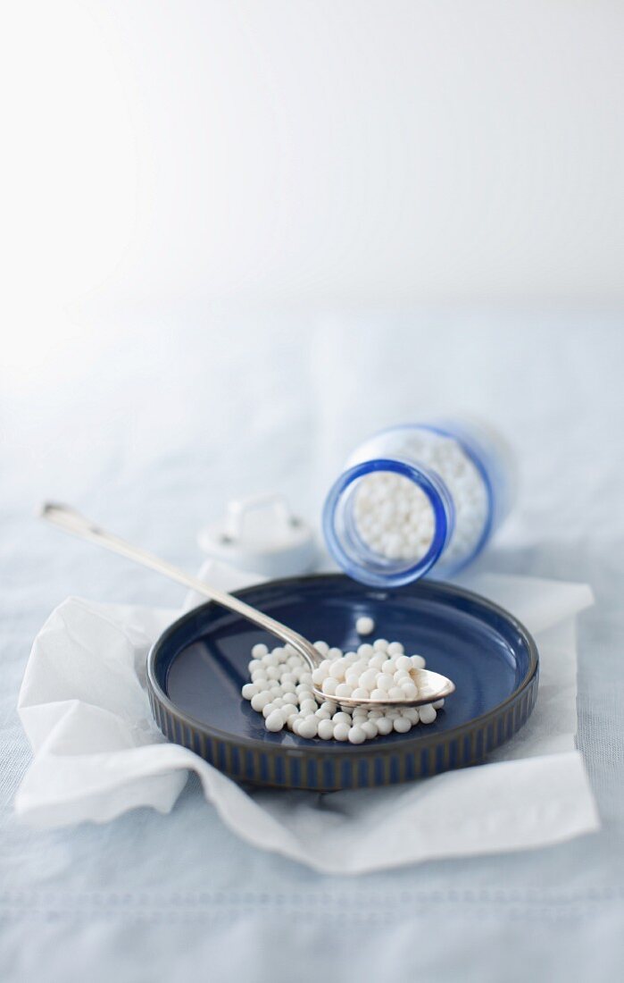 Tapioca Pearls Spilling from a Bottle into a Shallow Bowl with a Spoon