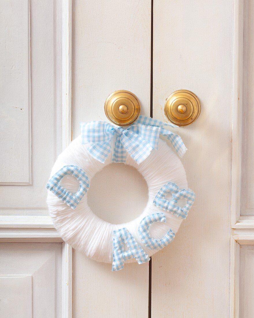 White wool wreath decorated with letters hanging on a door