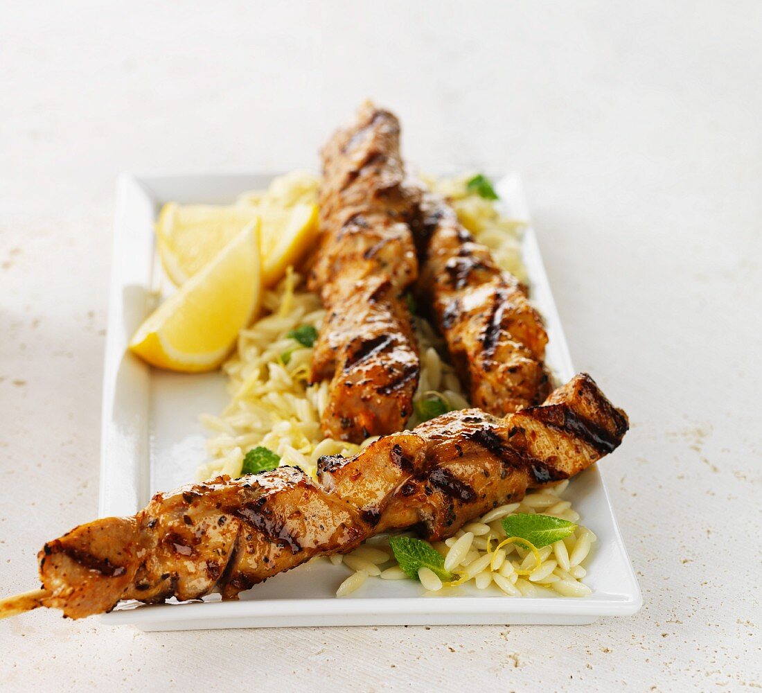 Souvlaki on a bed of rice with lemon wedges