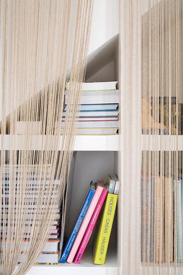 String curtain in front of fitted shelving below staircase