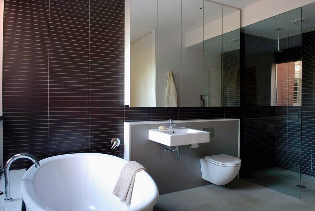 Designer bathroom with shower, anthracite strip tiles and large mirrored element