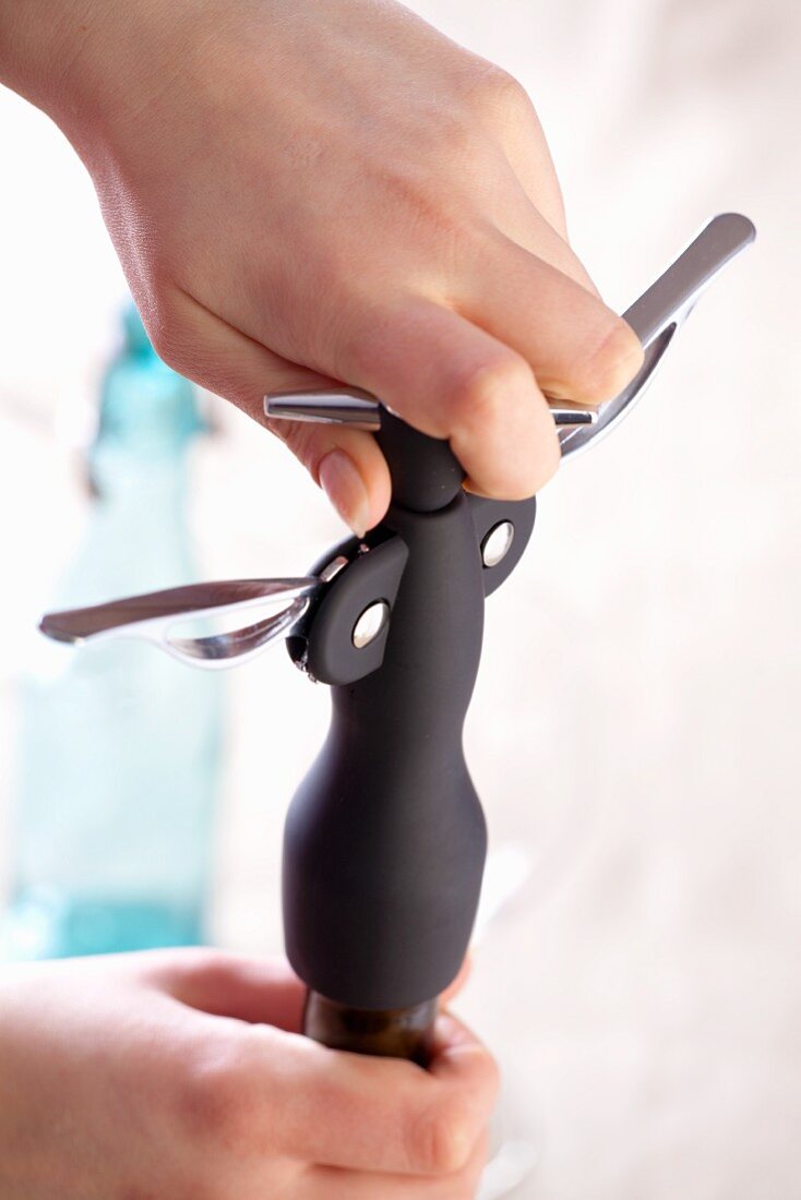 A wine bottle being opened with a corkscrew