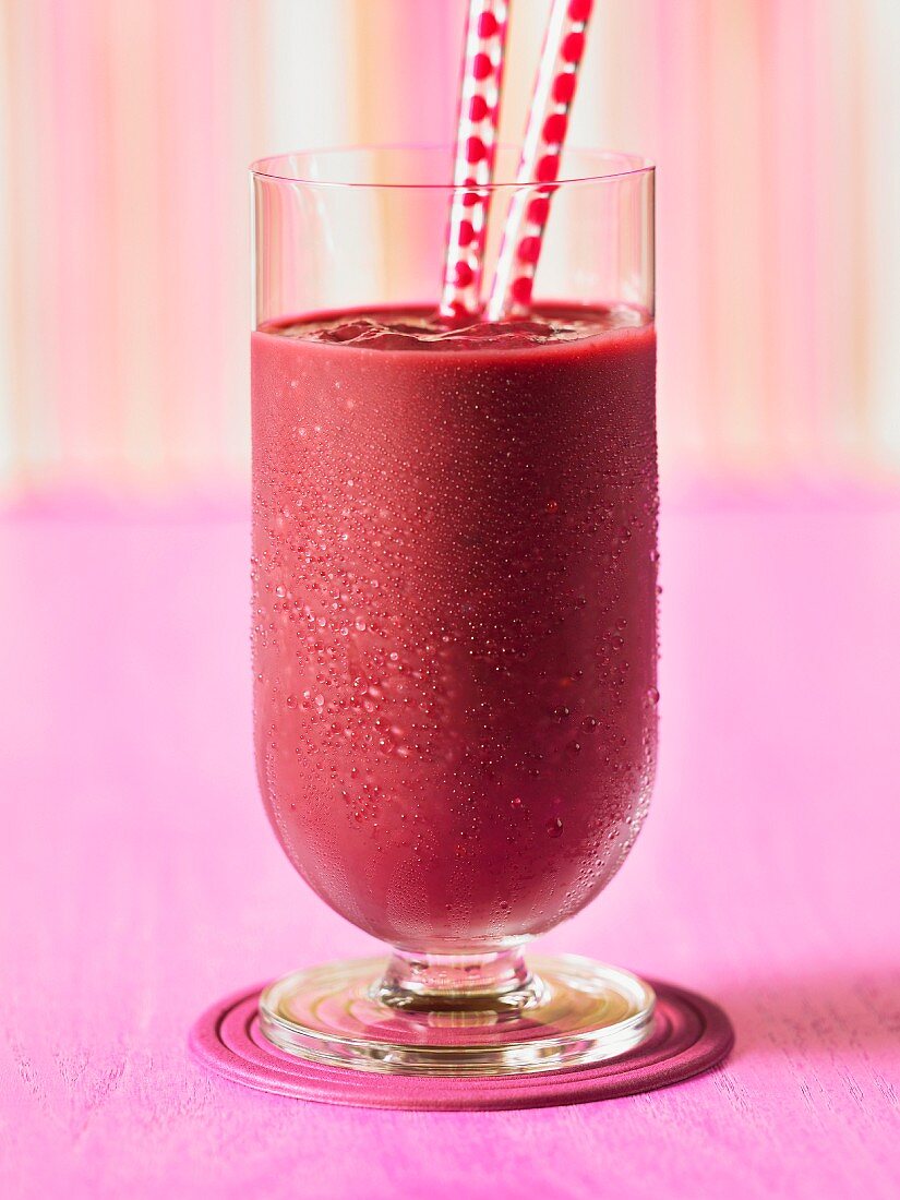 A glass of cherry smoothie with drinking straws