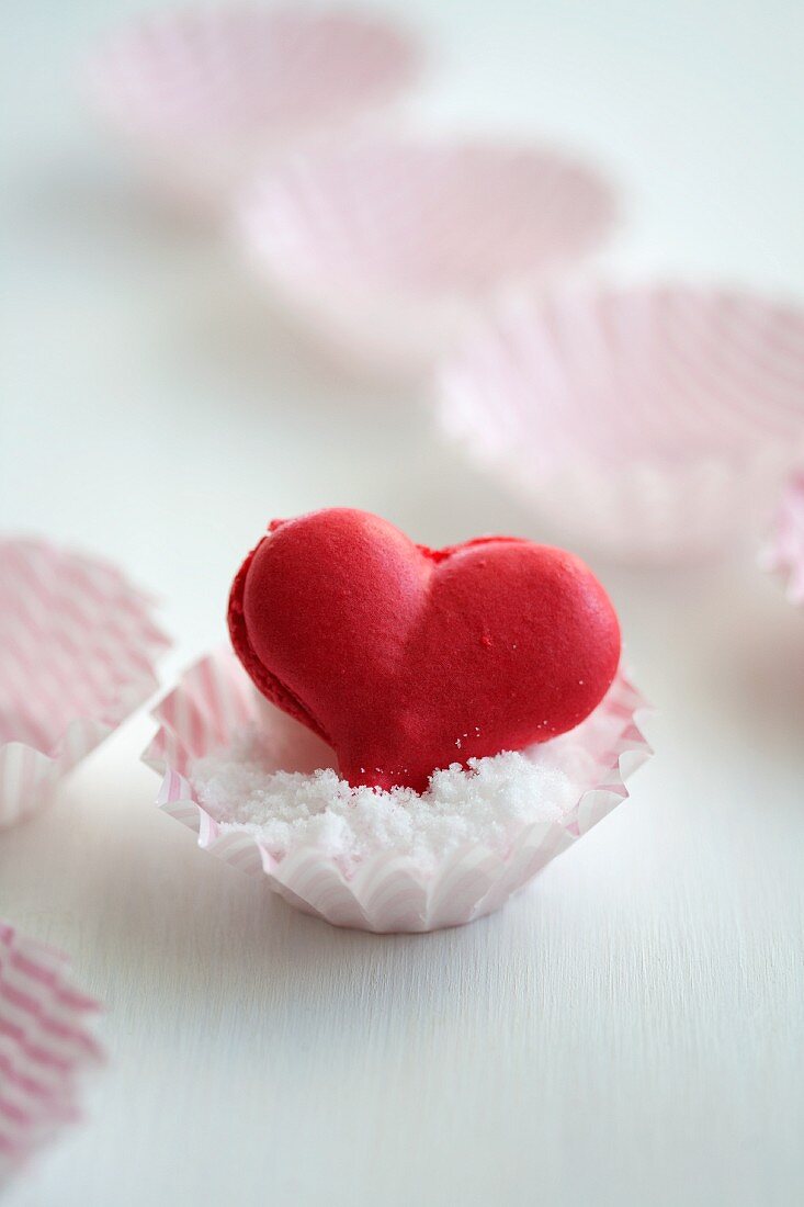 A heart-shaped strawberry macaroon in a paper case