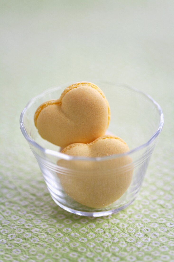 Heart-shaped peach macaroons in a small glass bowl