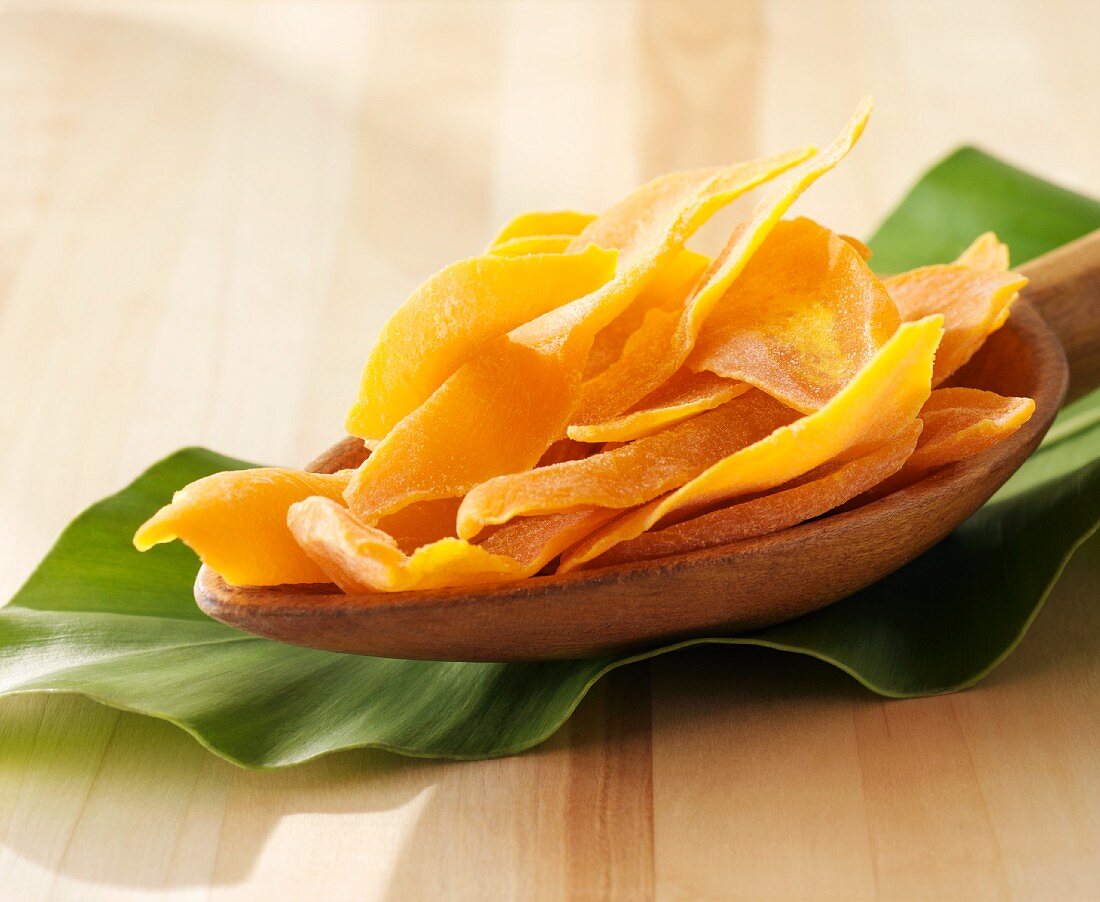 Dried mango slices on a wooden spoon