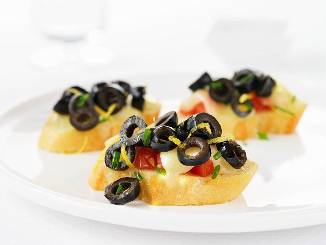 Crostini mit schwarzen Oliven, Tomaten und Mozzarella