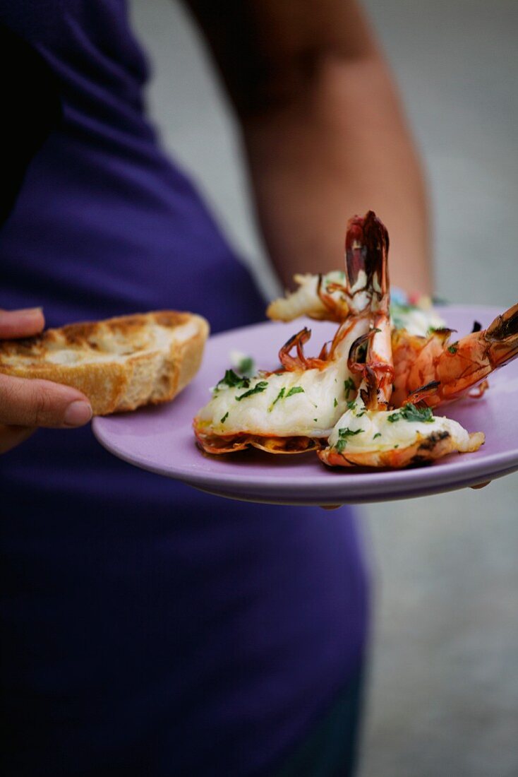 A woman holding a plate of barbecued king prawns