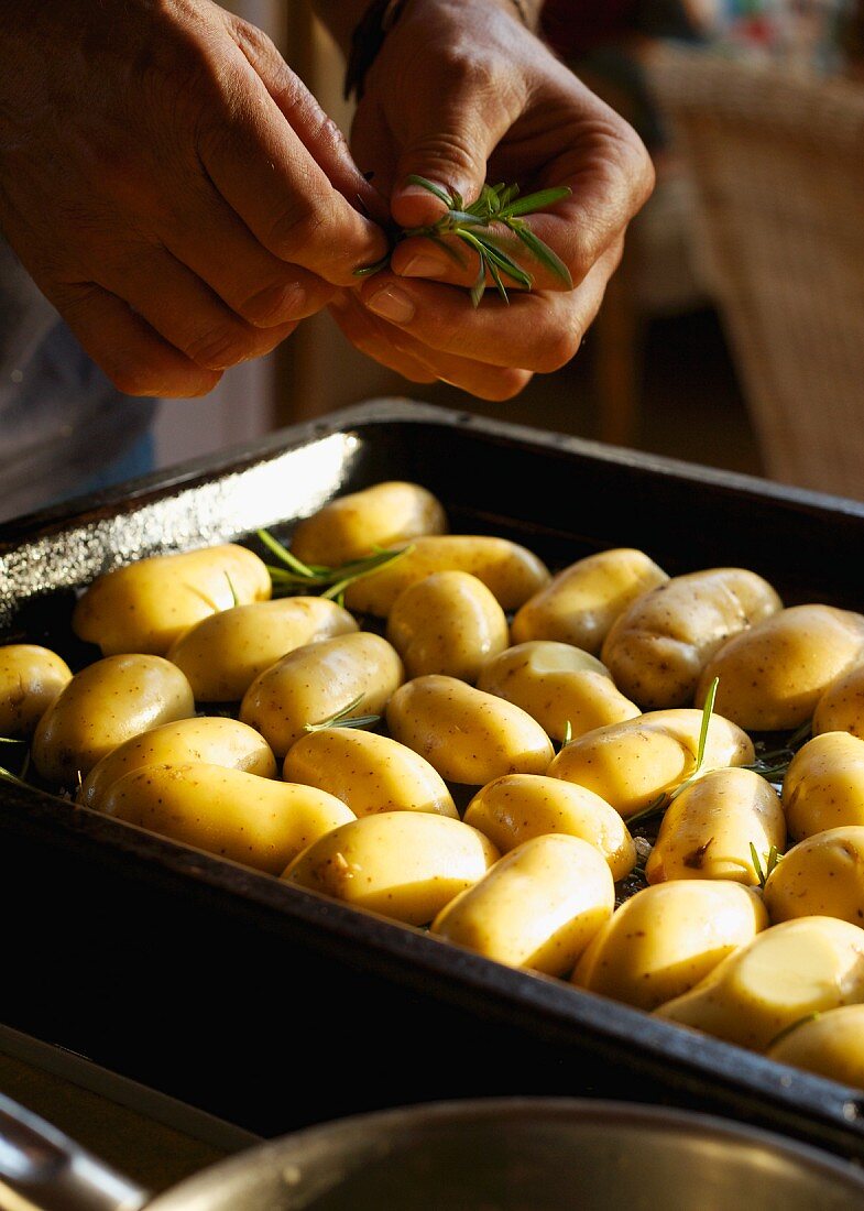 Potatoes being sprinkled with rosemary