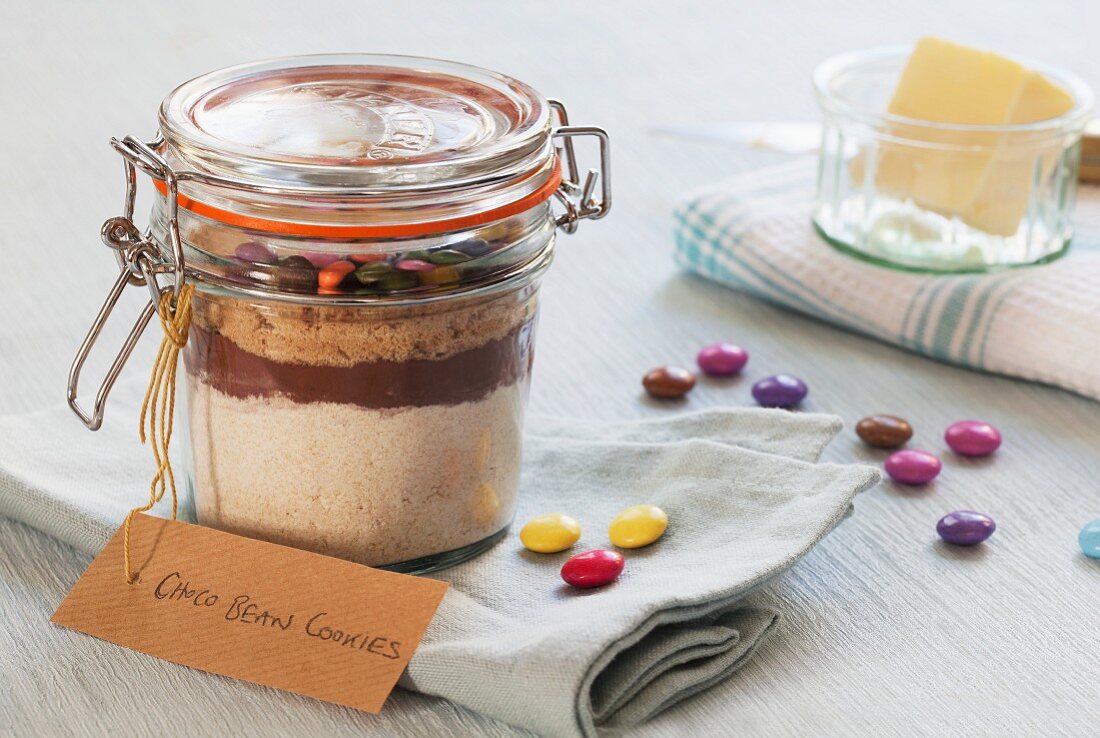 A preserving jar containing the dry ingredients for making chocolate biscuits with chocolate beans