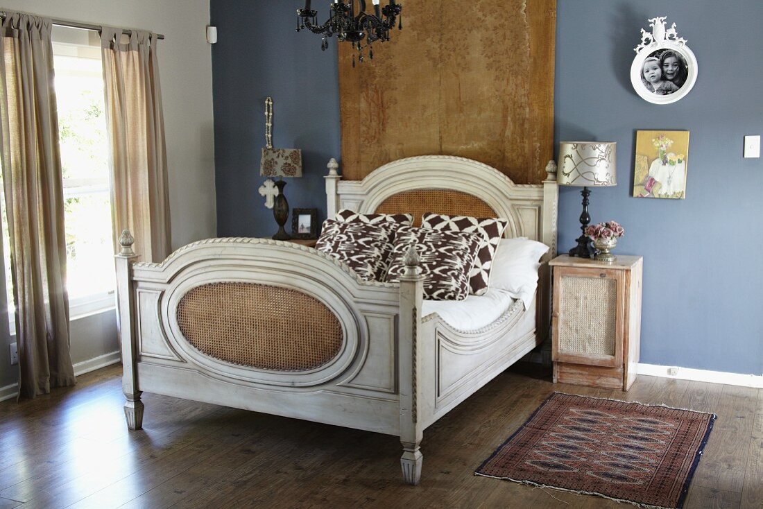 Antikes Doppelbett vor Wandbehang an blau getönter Wand in elegantem Vintage Schlafzimmer