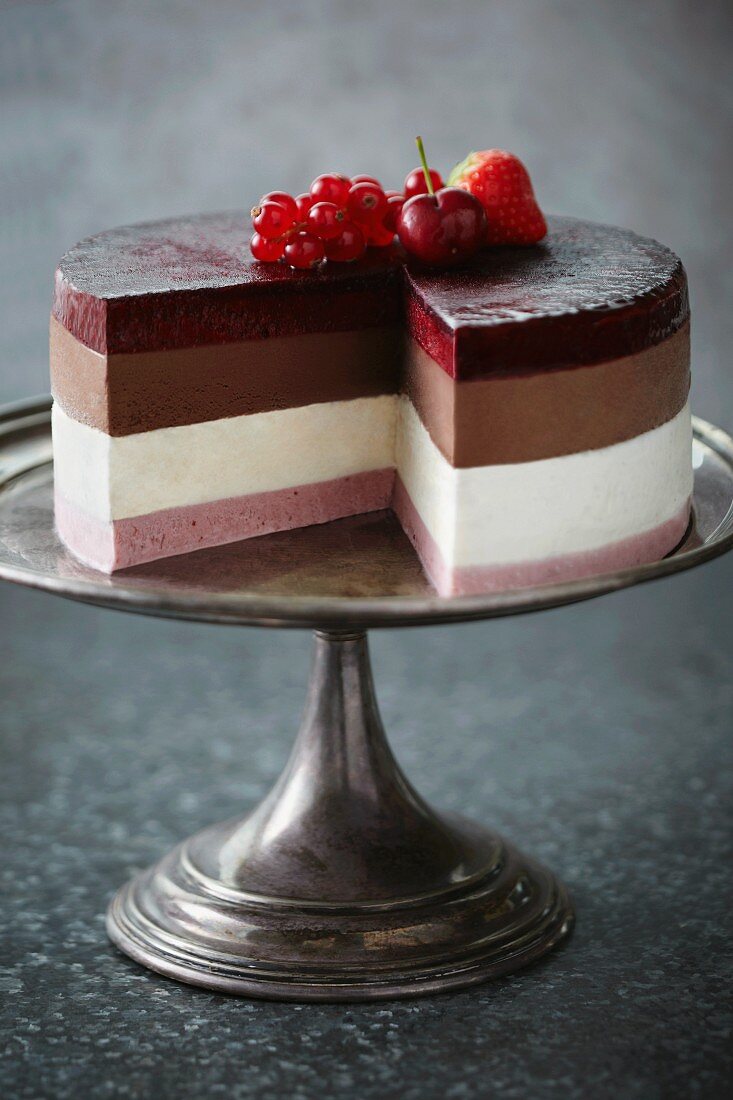 Layered ice-cream cake on a cake stand, with a slice missing