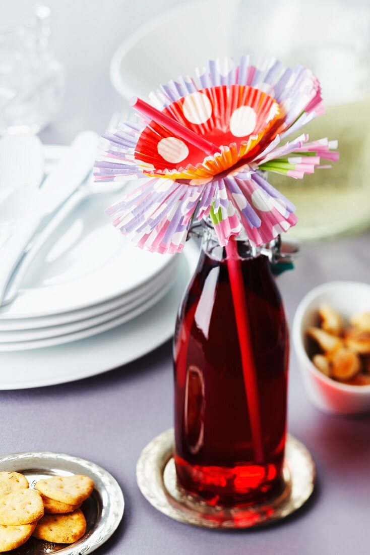 Getränkeflasche mit Strohhalm und Muffinförmchen als Blüte