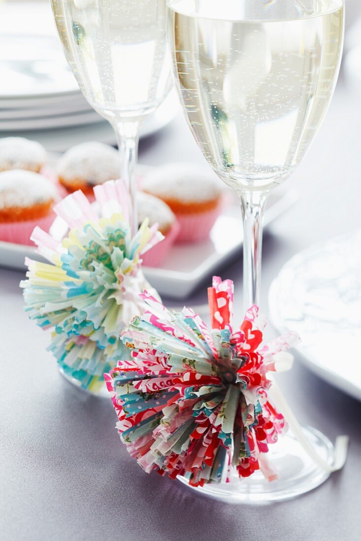 Pompoms made from paper cake cases decorating glasses of sparkling wine