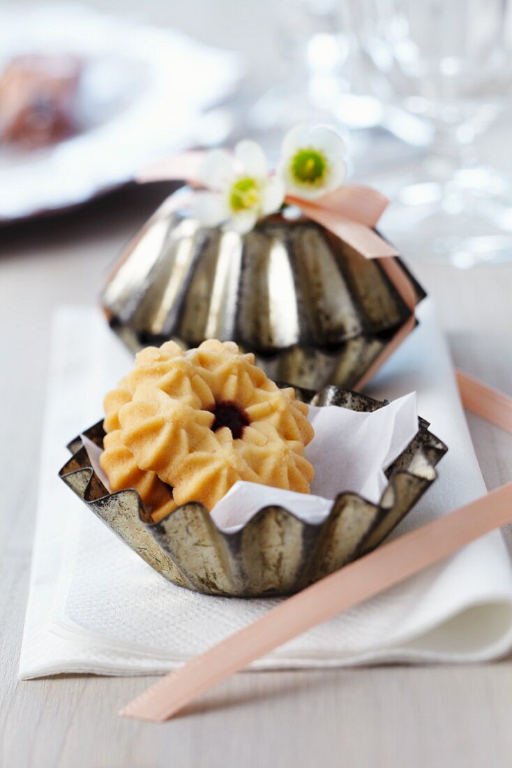 Small cake moulds filled with biscuits as guest favours