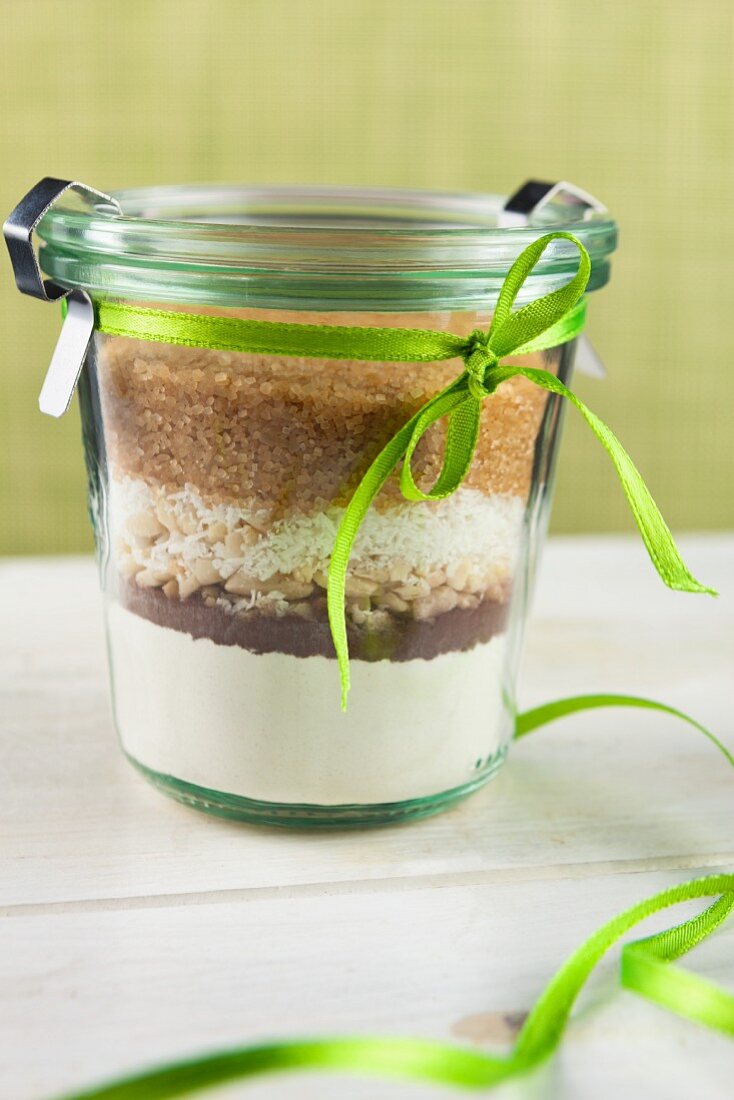 A preserving jar tied with a ribbon containing the dry ingredients for making coconut and nut biscuits