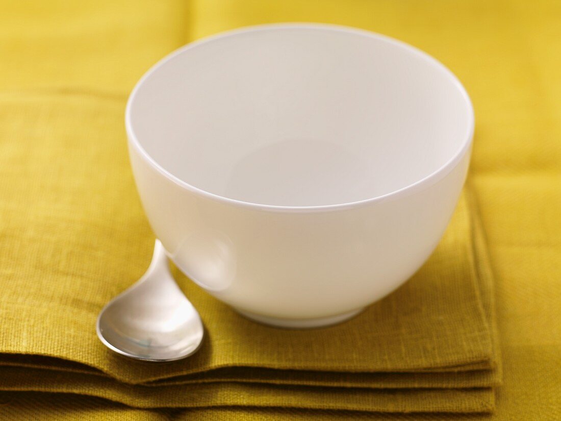 An empty soup bowl with a spoon on a napkin