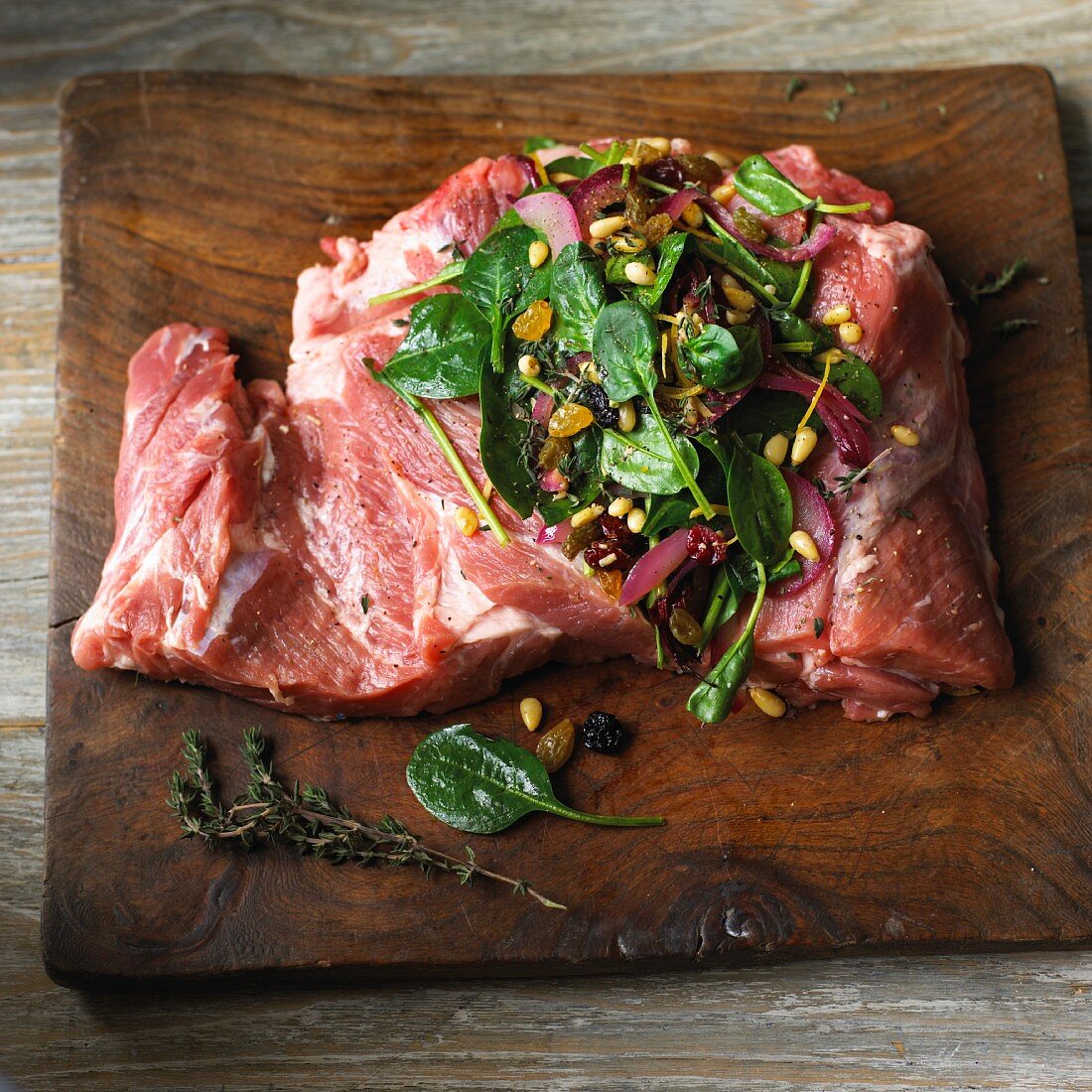 Raw pork shoulder and stuffing on a chopping board