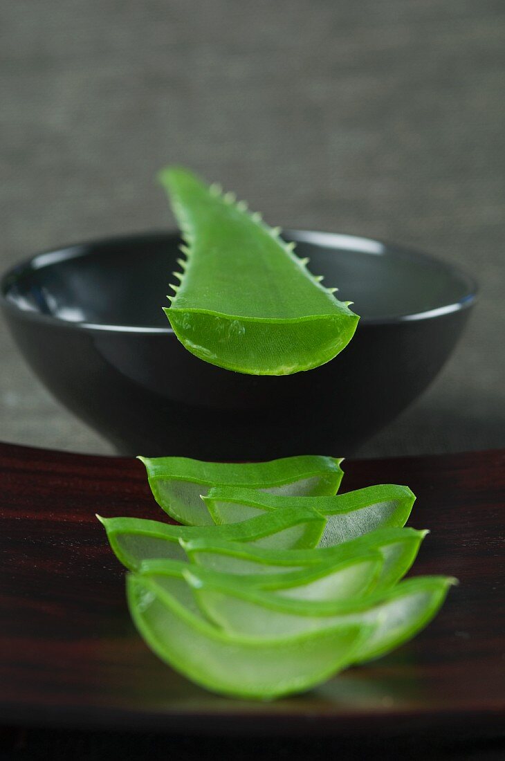 Sliced aloe vera shoots on a wooden board and on a bowl