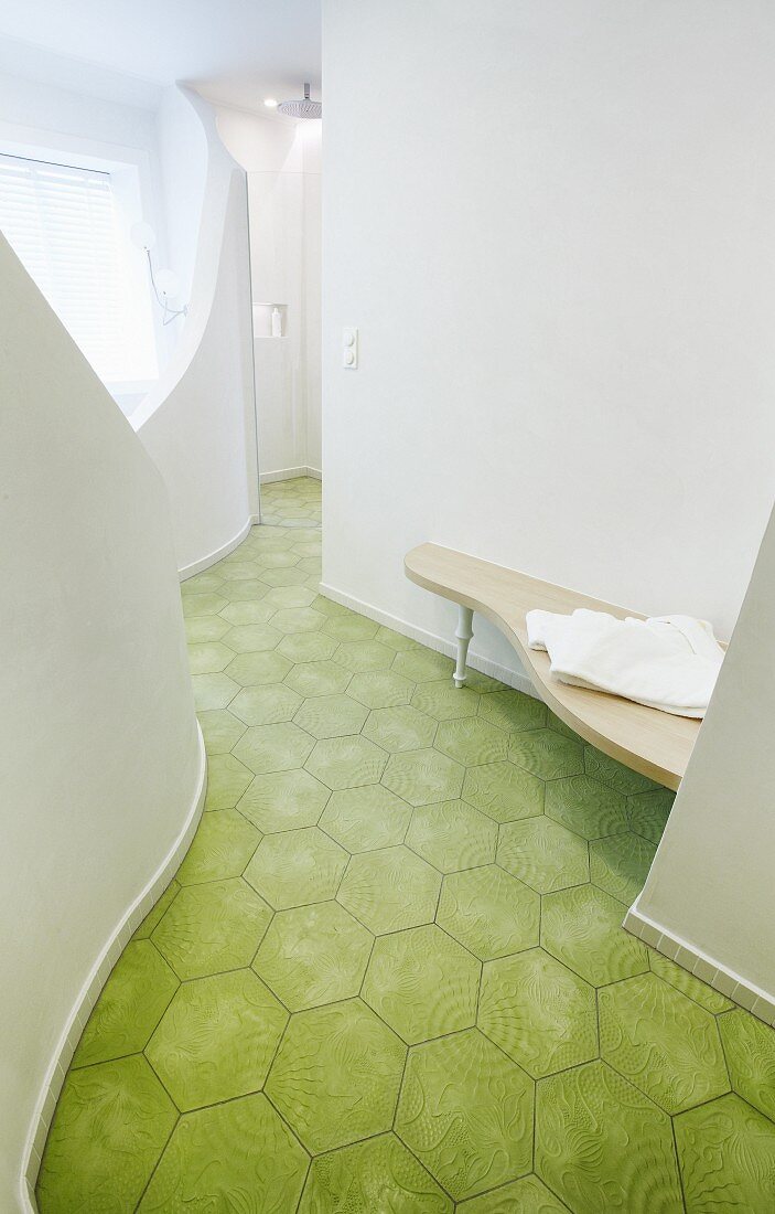 Curved bathroom installations and green, retro floor tiles