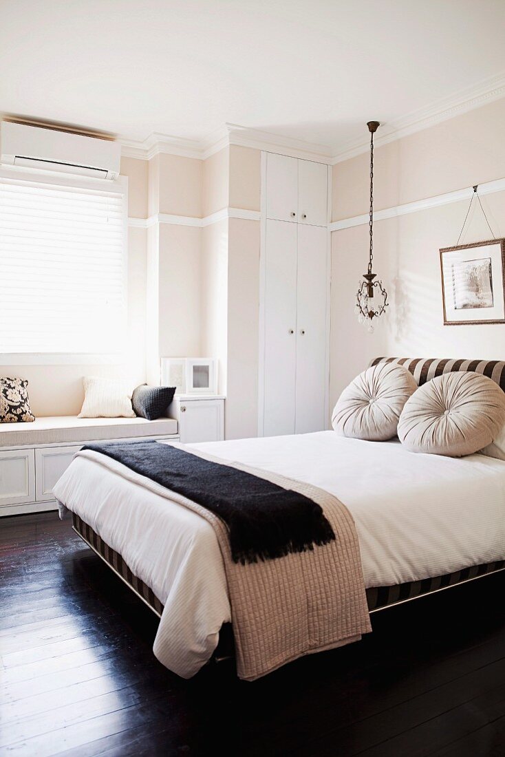 Delicate pastel pink combined with dark wooden floor and black accessories in elegant bedroom