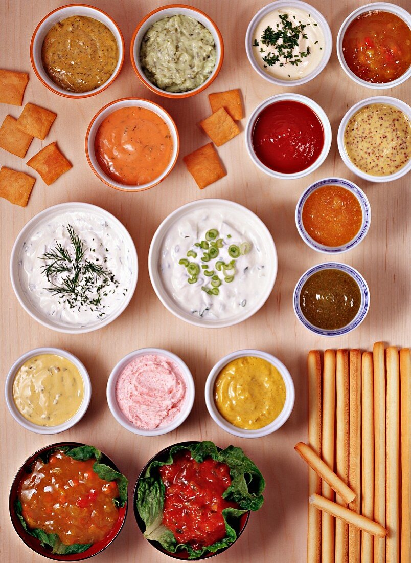 Lots of different dips in bowls with crackers and grissini