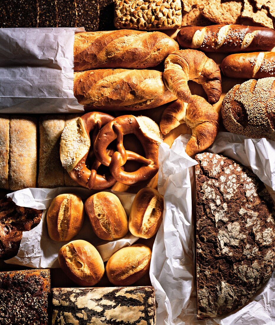 Verschiedene Brote, Brötchen, Brezeln und Croissants auf Pergamentpapier