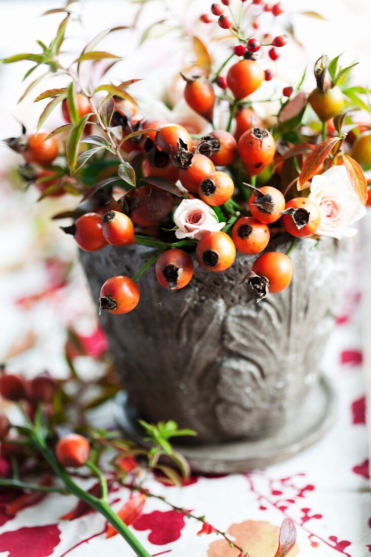 Late-summer bouquet with rosehips, roses and branches of spirea