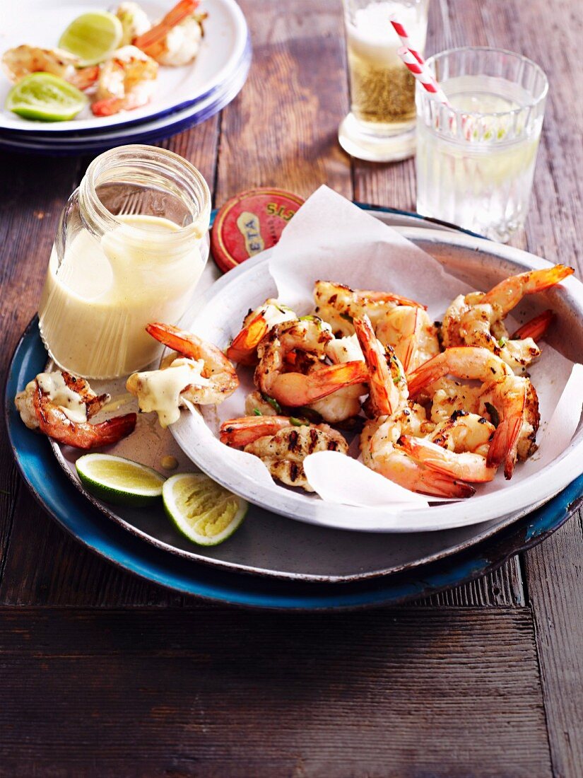 Grilled prawns with spicy mayonnaise and limes on a wooden table