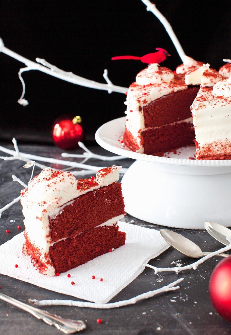 Red Velvet Cake, angeschnitten, mit Stück auf einem Teller zu Weihnachten