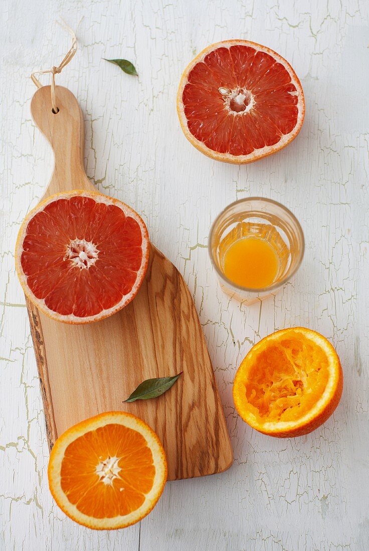 An orange and a grapefruit, cut in half, with orange juice squeezed from one orange half