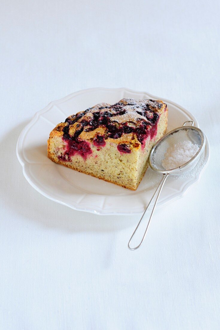 A slice of blueberry cake dusted with icing sugar