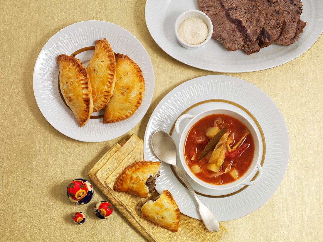 Borscht, served with meat pasties and a plate of sliced meat