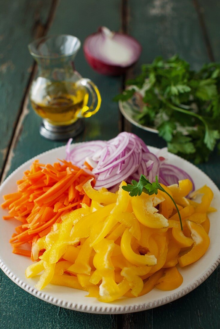 Geschnittene gelbe Paprika, Karotten und Zwiebeln auf Teller