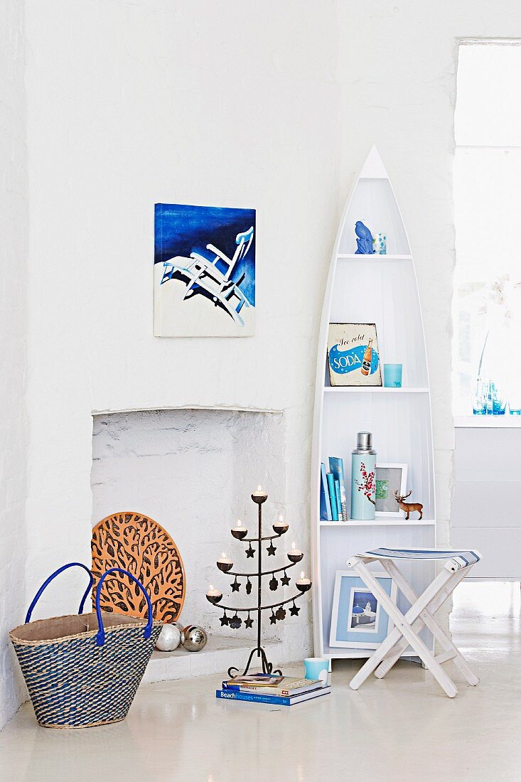 White, boat-shaped shelving, folding chair and metal candlestick in front of fireplace