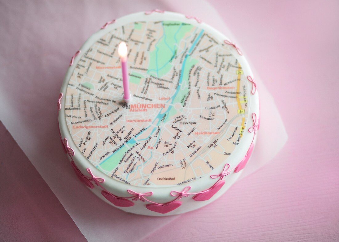 A small wedding cake topped with a city map and a symbolic candle