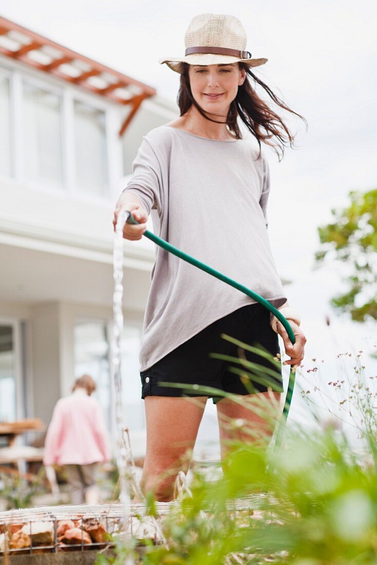 Frau giesst Blumen im Garten