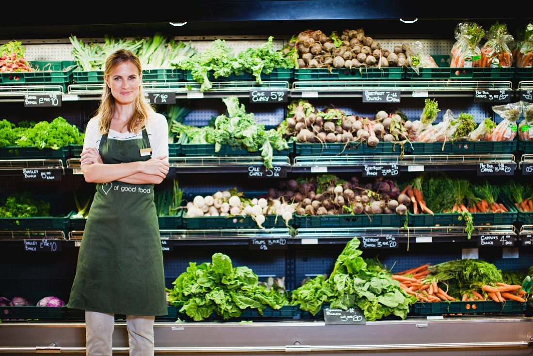 Verkäuferin steht in der Gemüseabteilung im Supermarkt