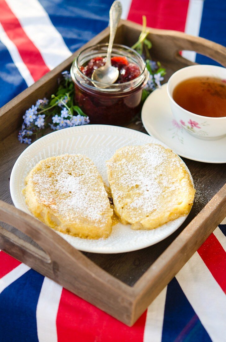 Holztablett mit Armer Ritter, Marmelade und eine Tasse Tee auf englischer Flagge