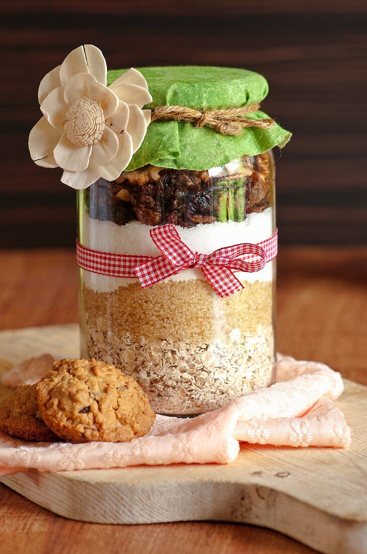 A jar containing dry ingredients for making walnut and oat biscuits with chocolate chips