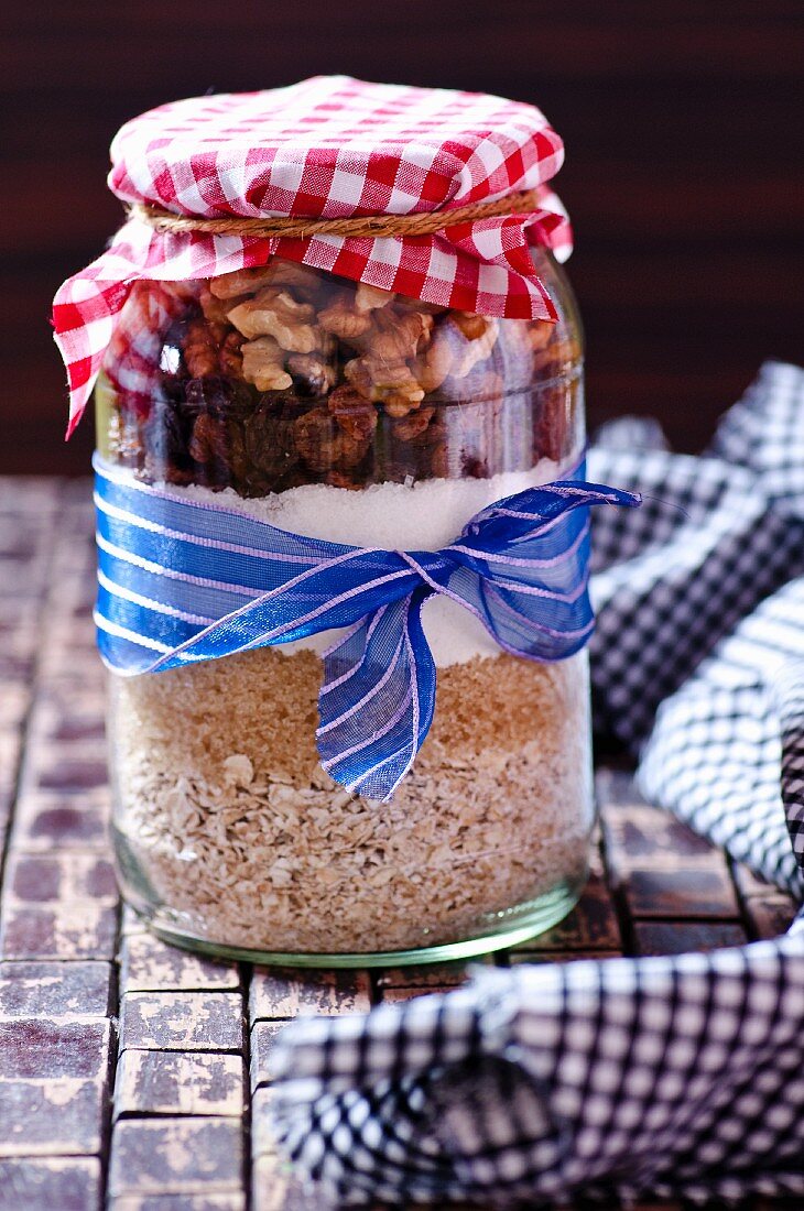 A jar containing dry ingredients for making walnut and oat biscuits with chocolate chips