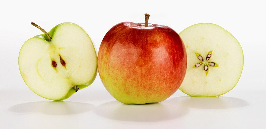 Apfel ganz und einmal quer und längs durchgeschnitten